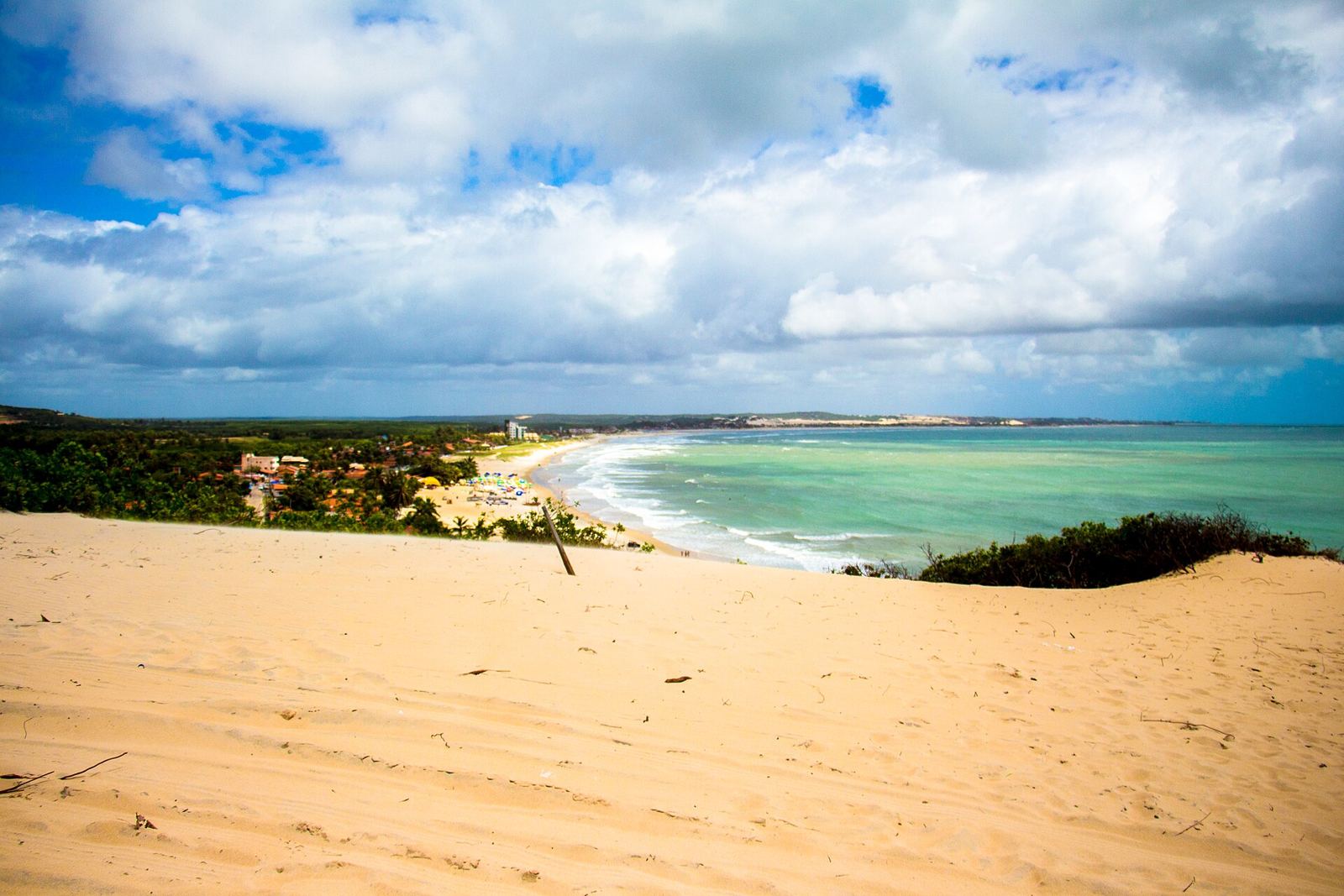 Dunas de Genipabu com areia clara em frente ao mar azul no litoral norte de Natal