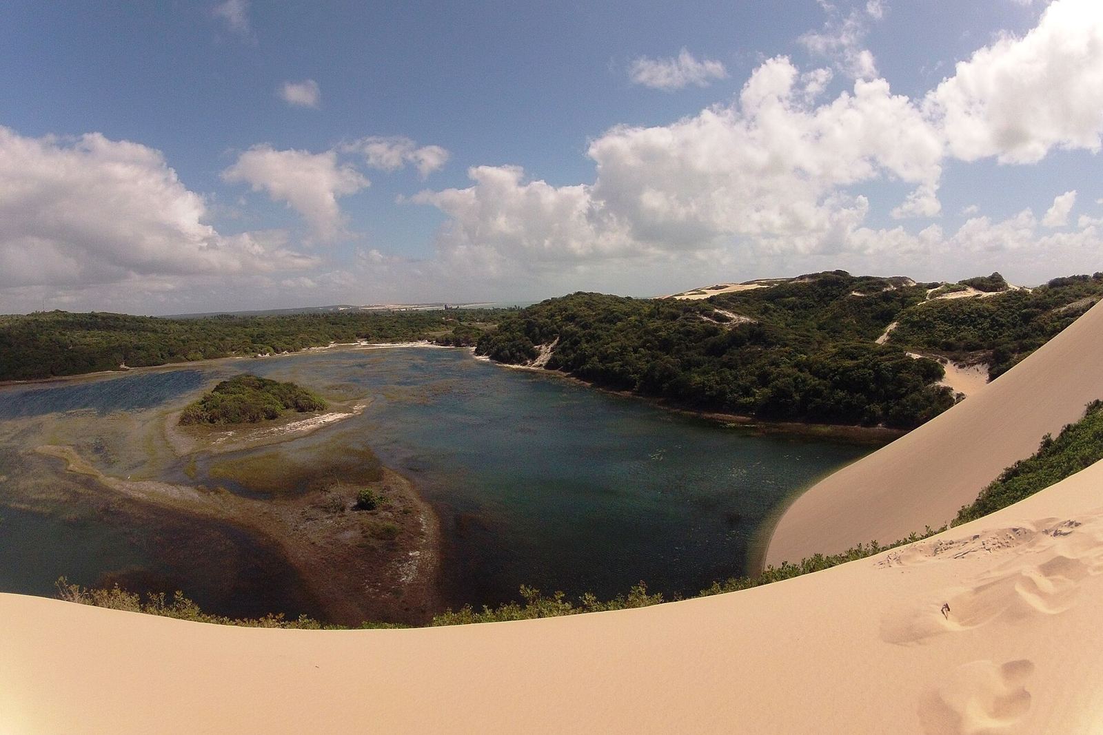 Lagoa de Pitangui com água escura e calma cercada por dunas brancas no litoral norte de Natal