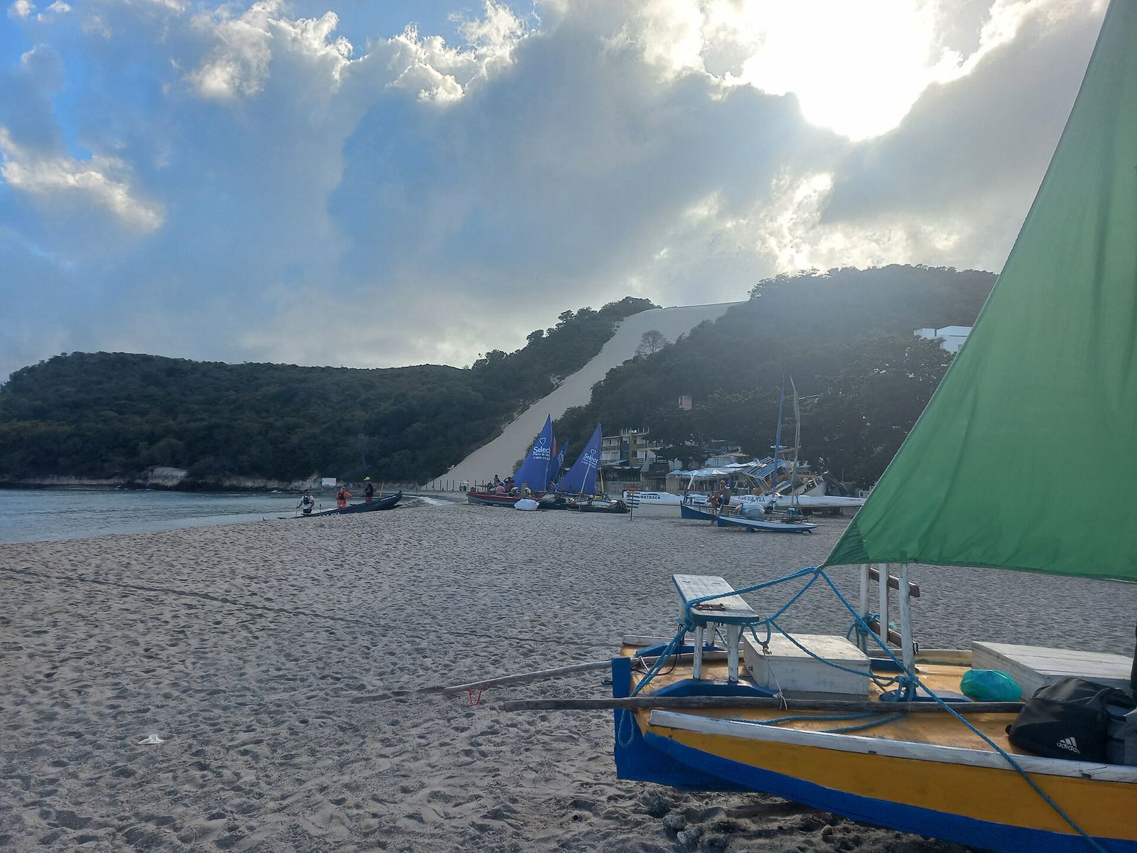 Morro do Careca, grande duna de areia clara, com jangada colorida na beira do mar de Ponta Negra em Natal